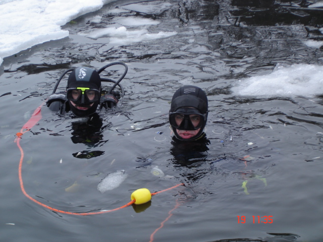 Na pierwszym planie instruktor WOPR Rafał Gutkowski podczas nurkowania pod lodem
